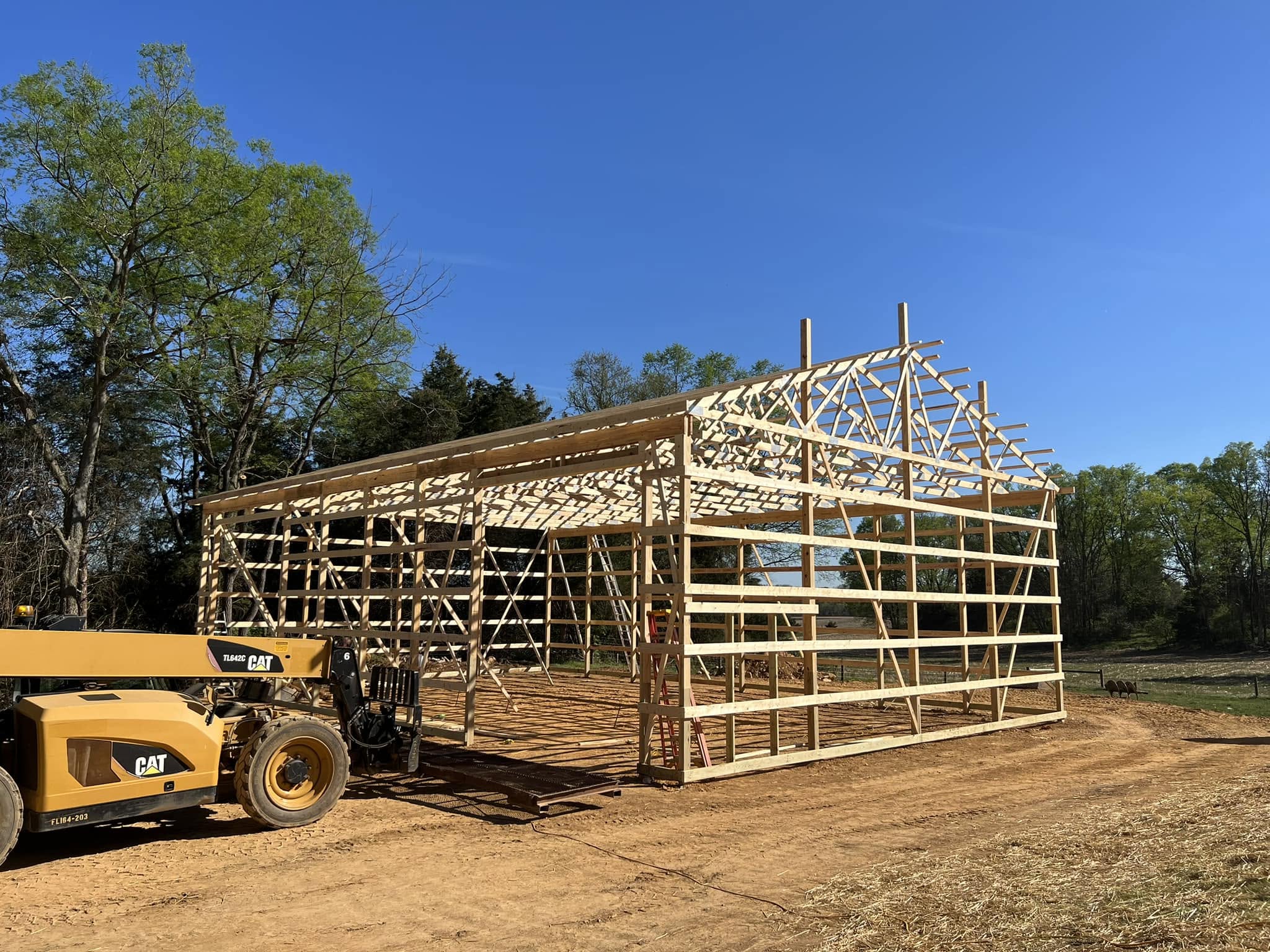 Post-frame pole building under construction with wall framing and roof trusses set, built by Pole Buildings Plus in Maryland