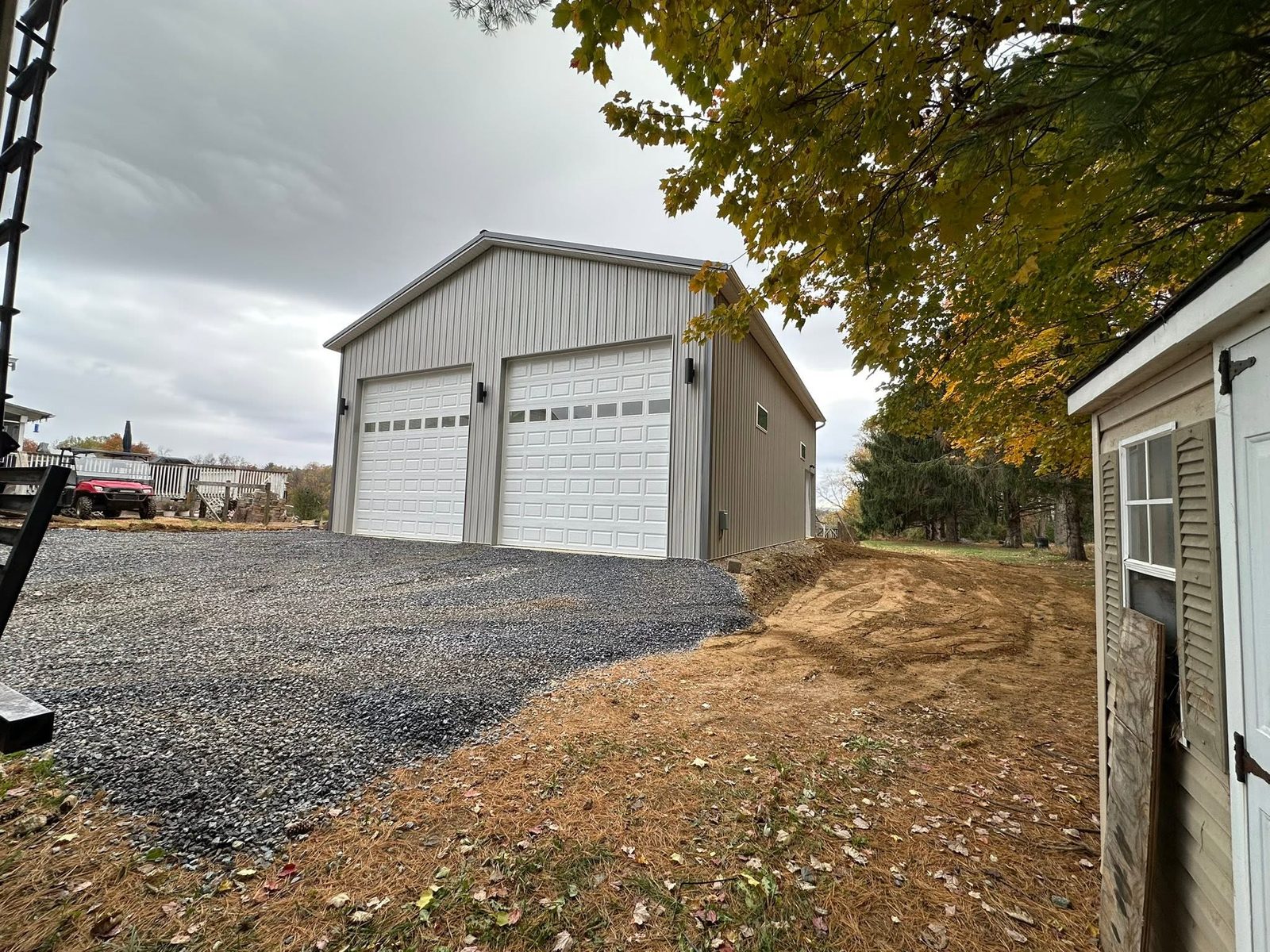 Two-car detached post-frame garage with white overhead doors in Maryland